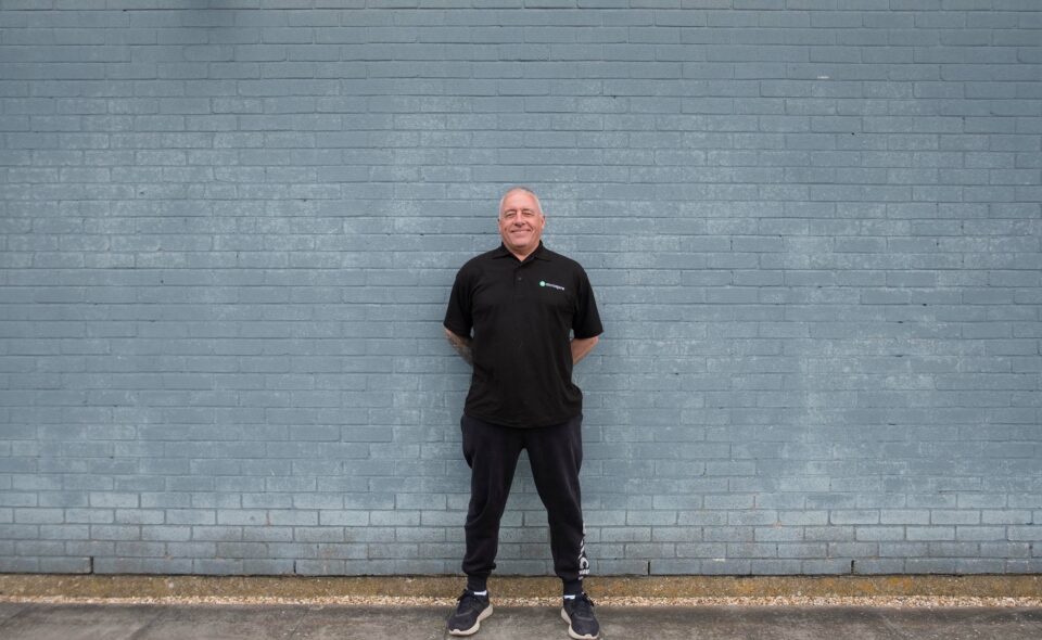 picture of a man standing against a blue brick wall