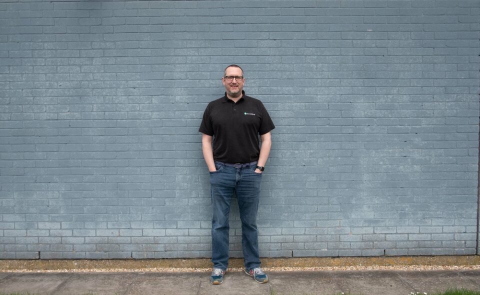 man standing against blue brick wall